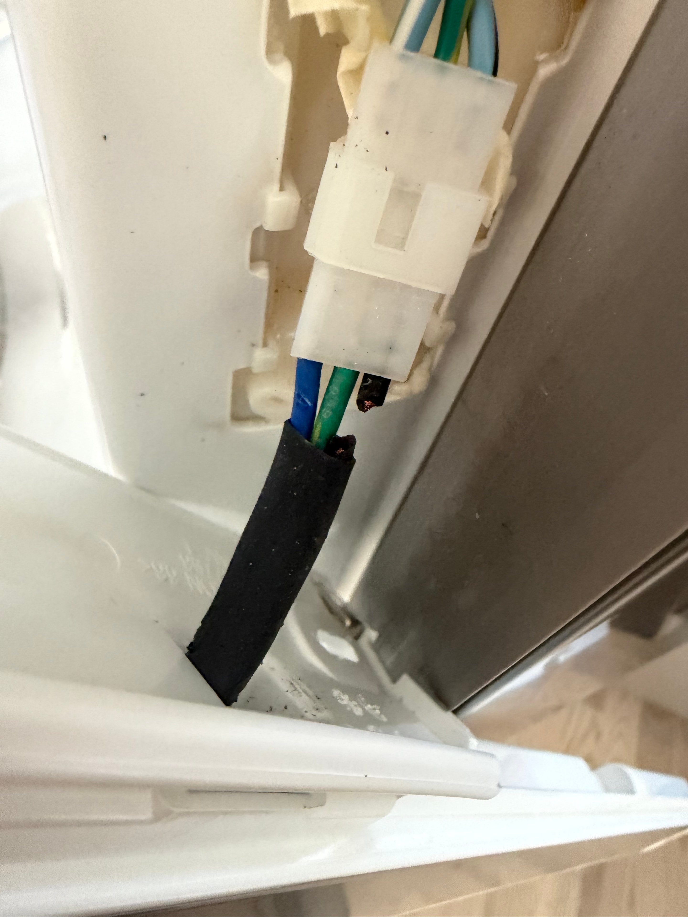 Broken Frigidaire refrigerator mullion heater wiring harness showing electrical arcing damage and melted insulation