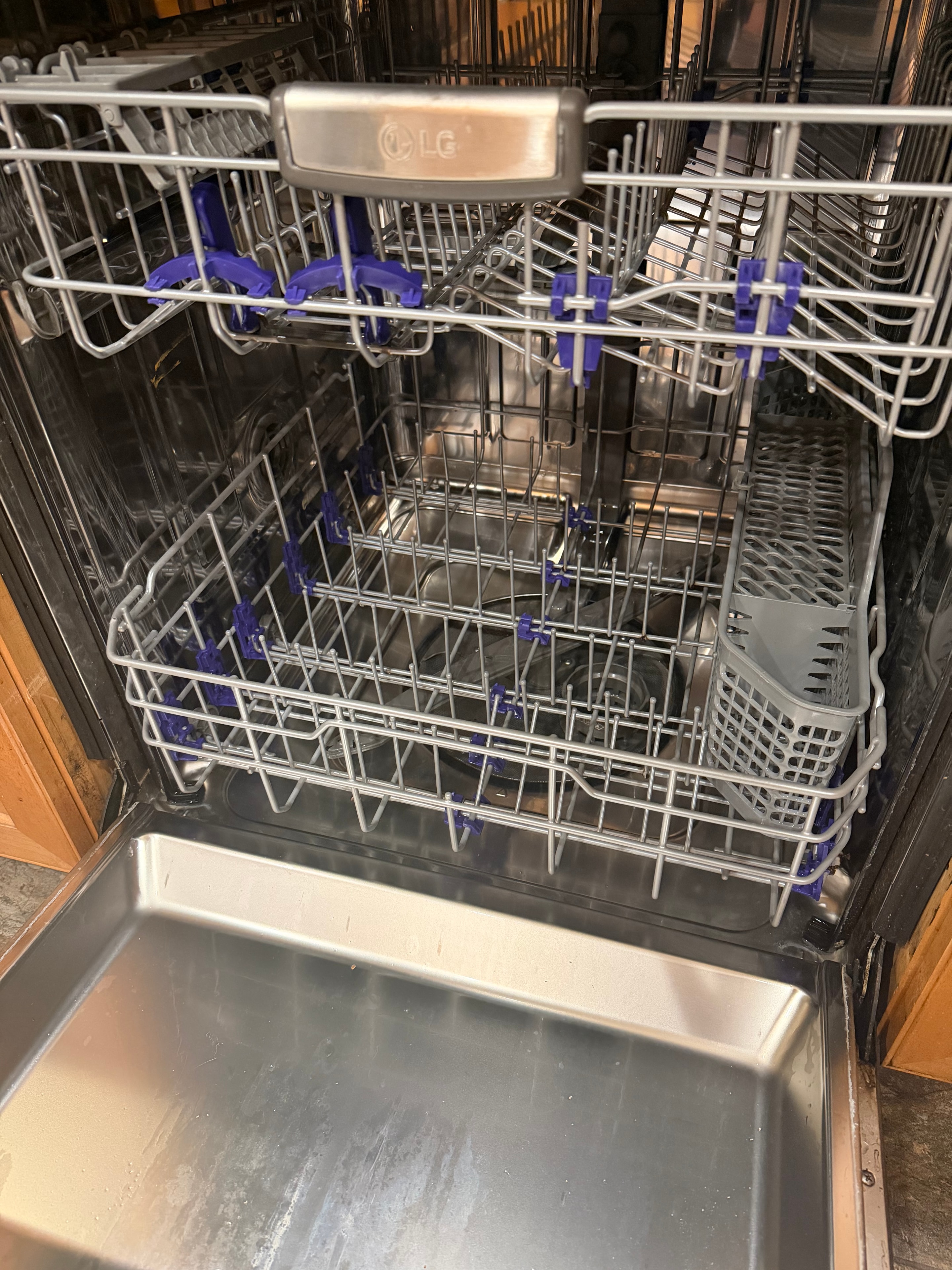 LG dishwasher interior open showing stainless racks and blue spray arms after repair in Park Hill Denver